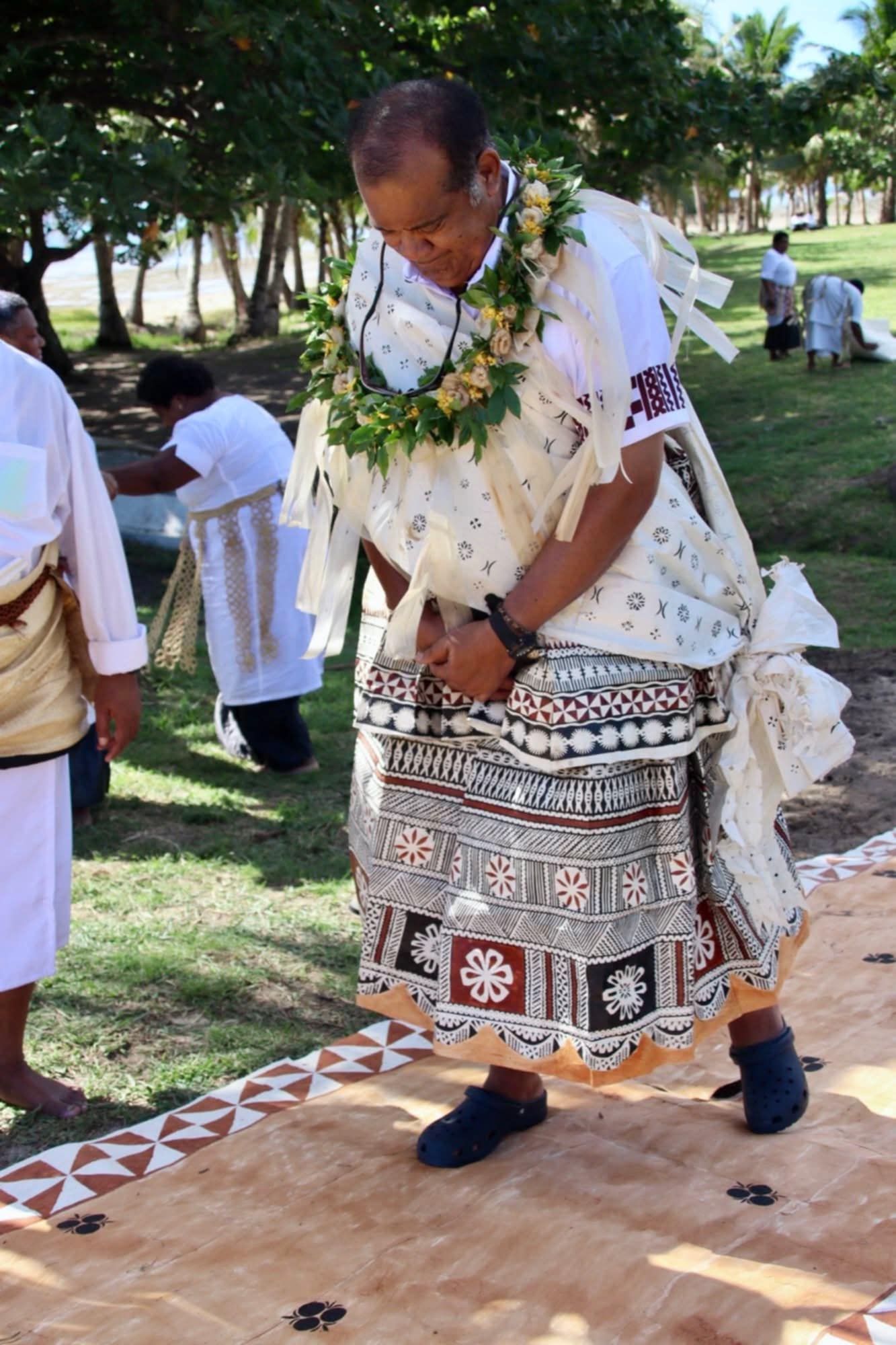 Man, tribal chief, with an traditional attire, walking on masi. Other tribes man also shown